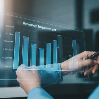 Analyzing Revenue Improvement Hands interact with a transparent digital display showing a bar graph titled Revenue Improvement indicating growth over time.